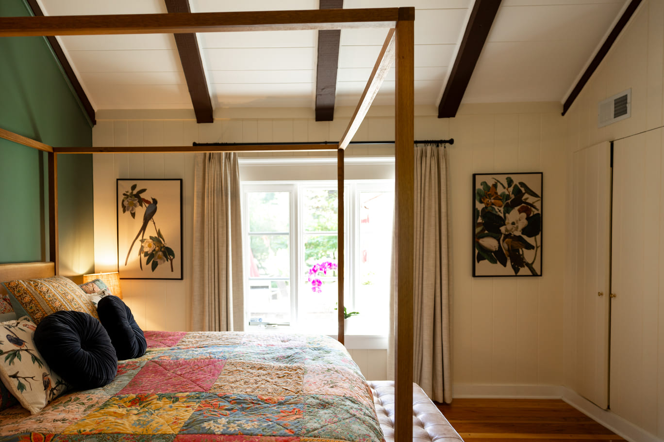 Bed with canopy bed frame in bedroom with vaulted ceilings and white and green walls