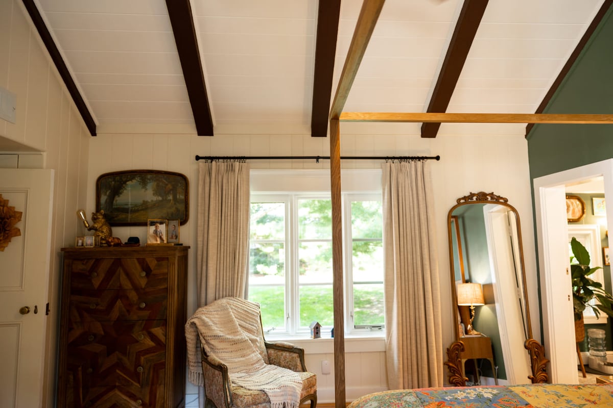 Bedroom with vaulted ceilings and wooden canopy bed frame with white and green walls