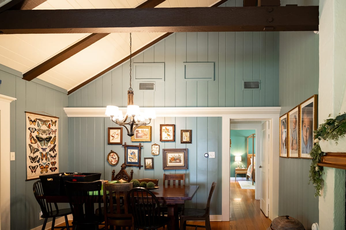 Dining room with dark wood table, vaulted ceilings, light blue walls with white moldings and doorframe