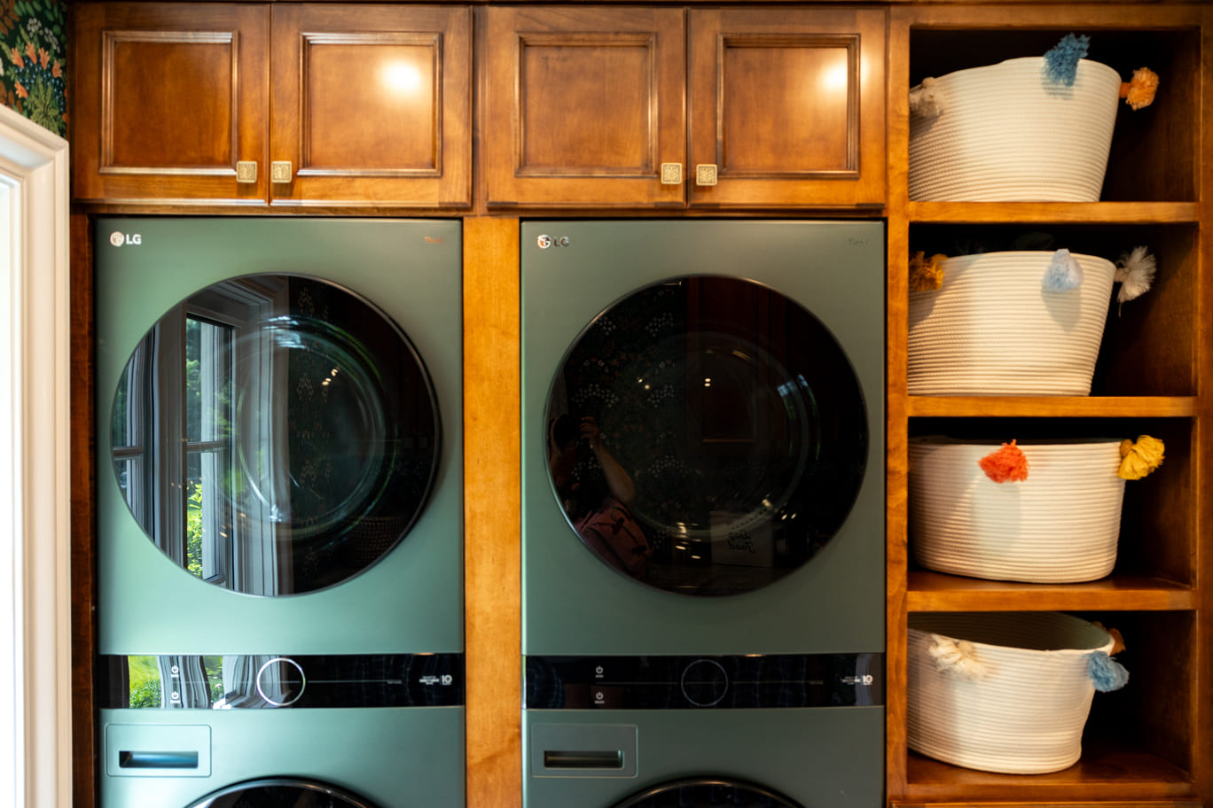 Green washer & dryer with wooden cabinetry and shelving in laundry room