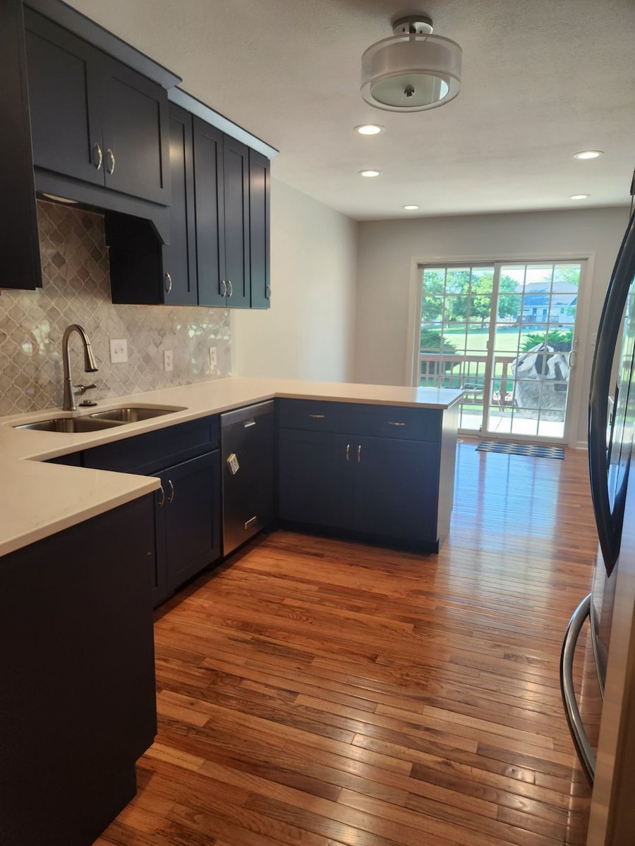 Kitchen Remodel With White Countertops and Blue Cabinetry With Stainless Steel Fixtures By True Craft Remodelers