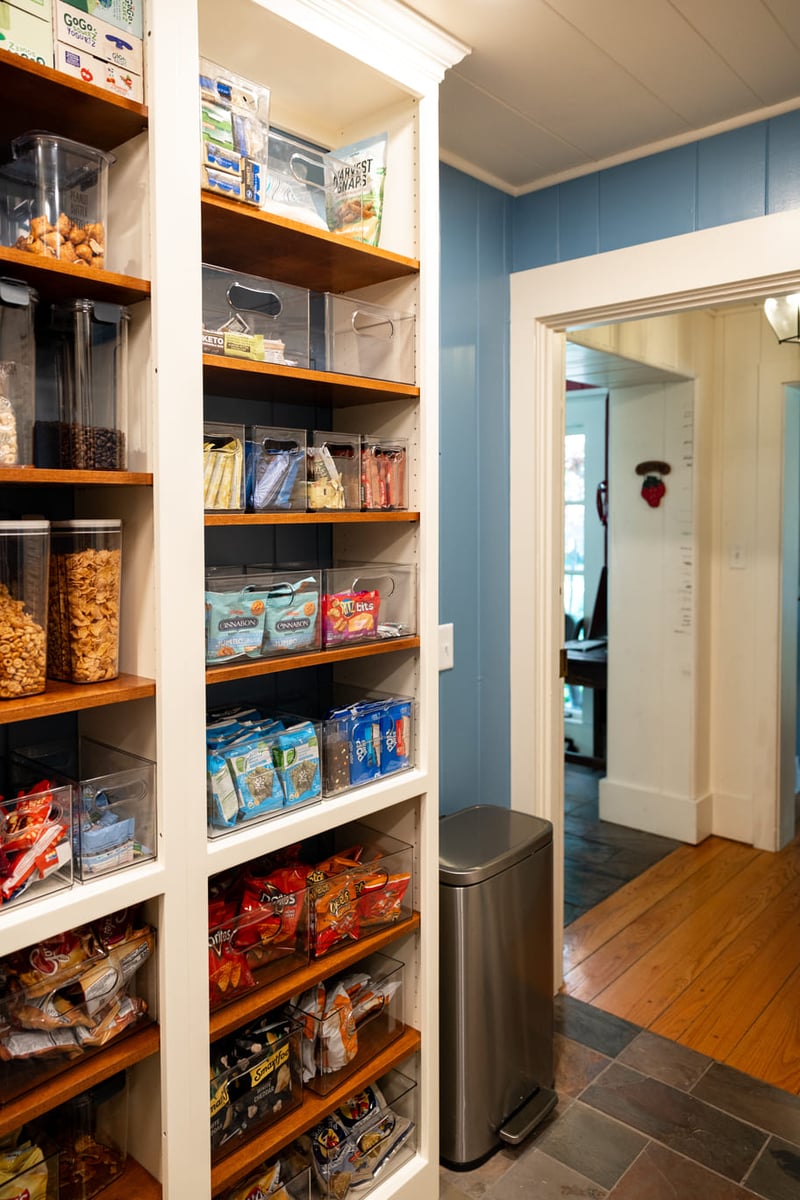 Pantry with wooden shelving, white cabinetry and blue walls
