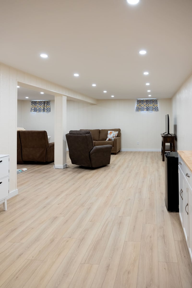 Basement remodel with bown couch and light wood floors
