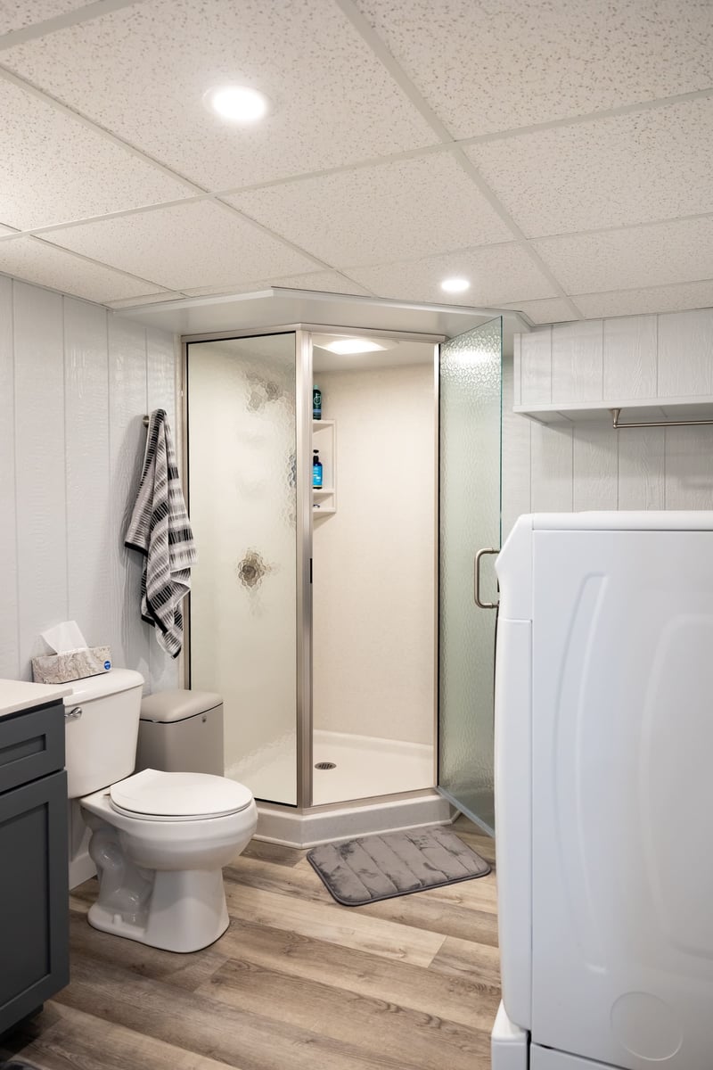 Bathroom with laundry appliences and small shower in basement remodel