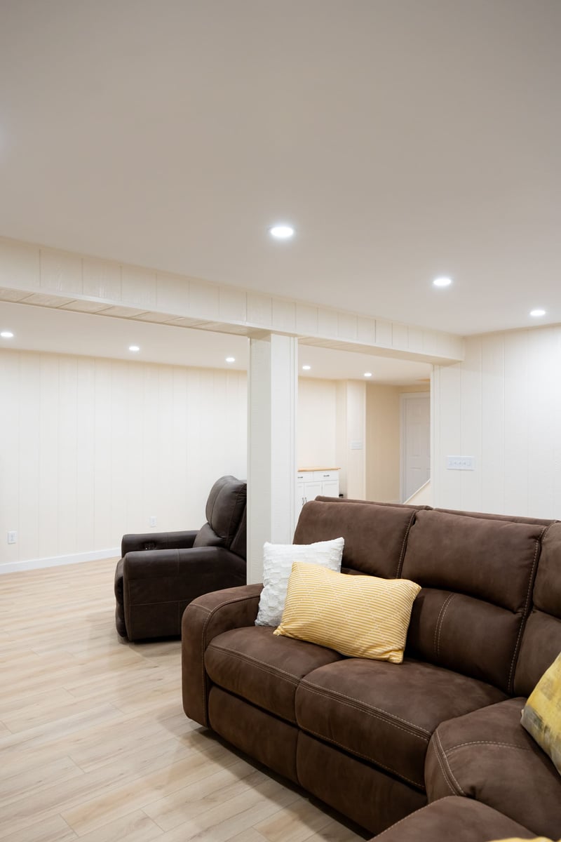 Dark brown recliner and brown couch in large open basement remodel