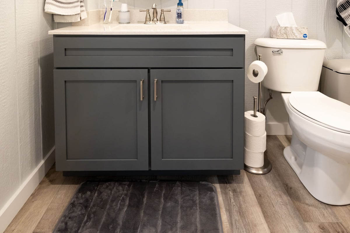 Dark grey vanity with white countertops and white toliet