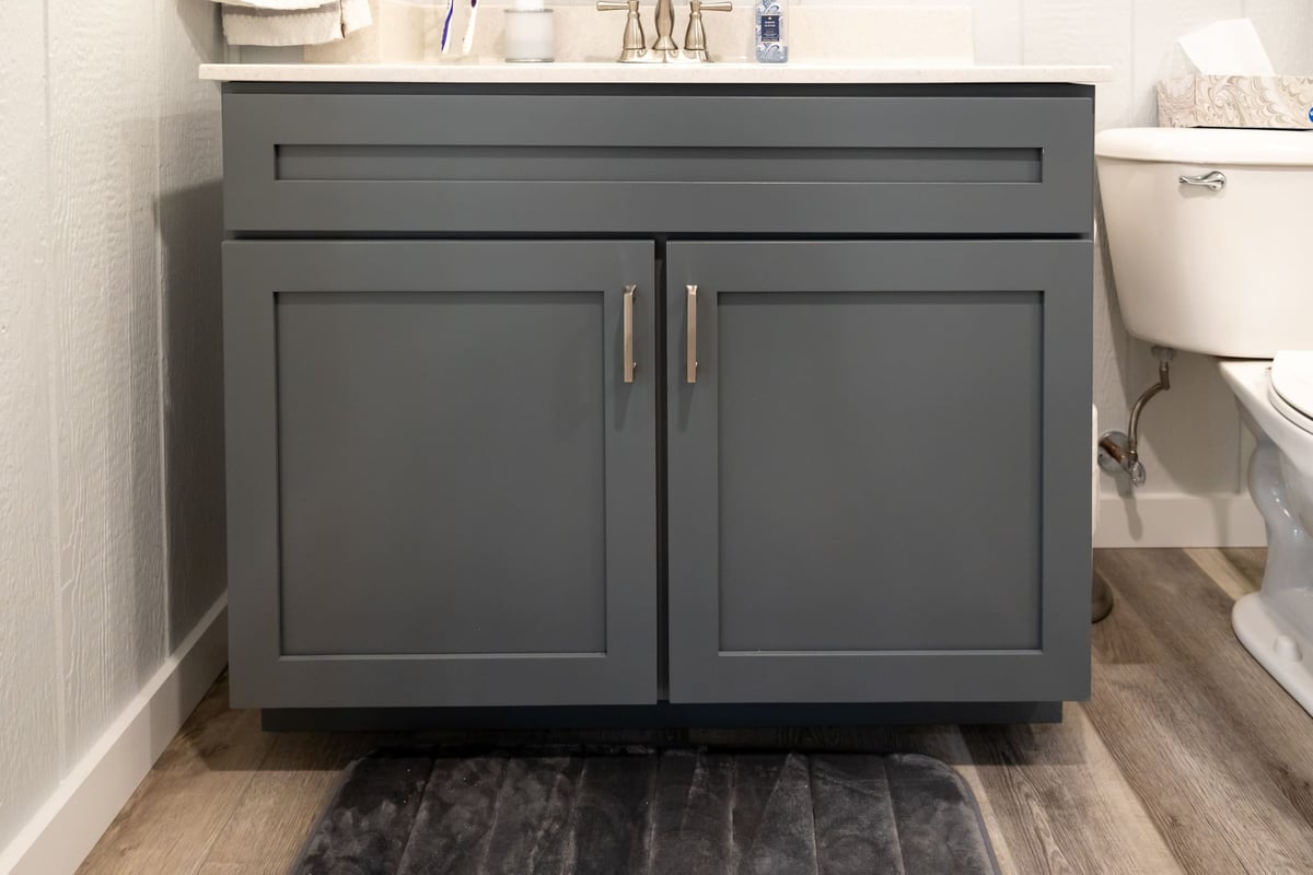 Grey cabinets with white countetop vanity with grey rug in bathroom in basement remodel