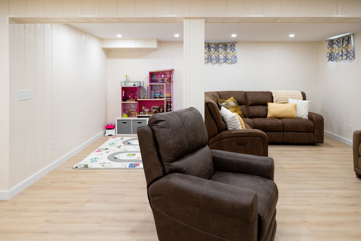Kids play area in basement remodel with brown couch & chair