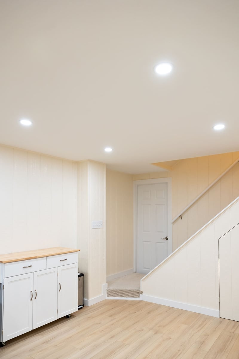 Light wood countertop, white door and stairway leading to first floor from basement remodel