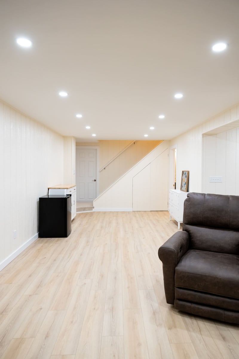 Mini fidge, brown chair, and stairway leading to first floor from basement remodel