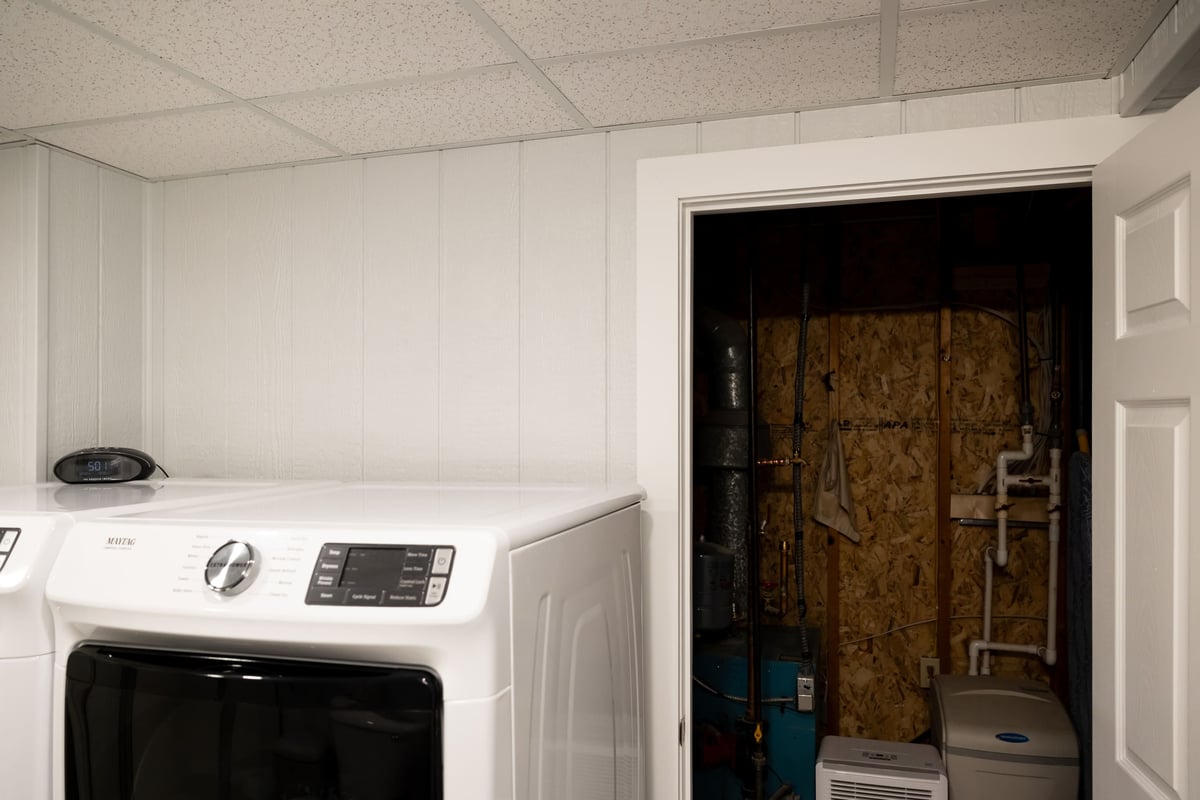 Open door to water closet next to washer & dryer in basement remodel