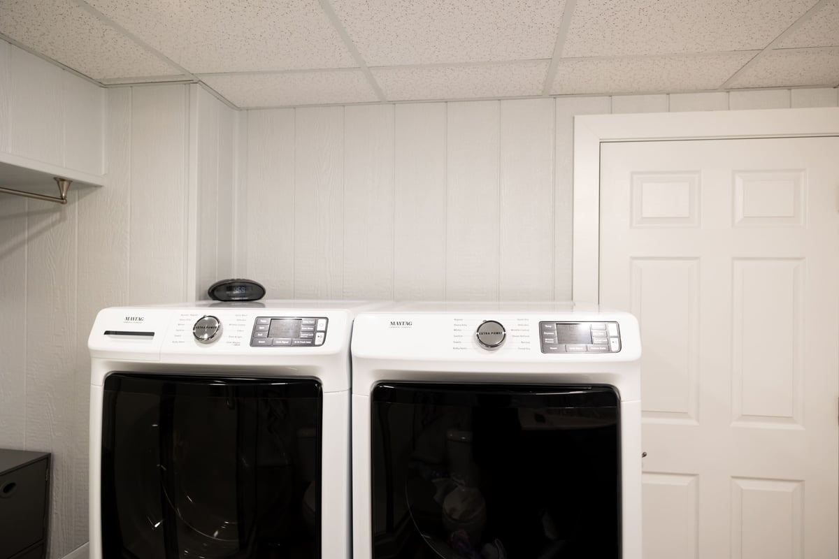 Washer & dyer in bright white laundry room in basement remodel