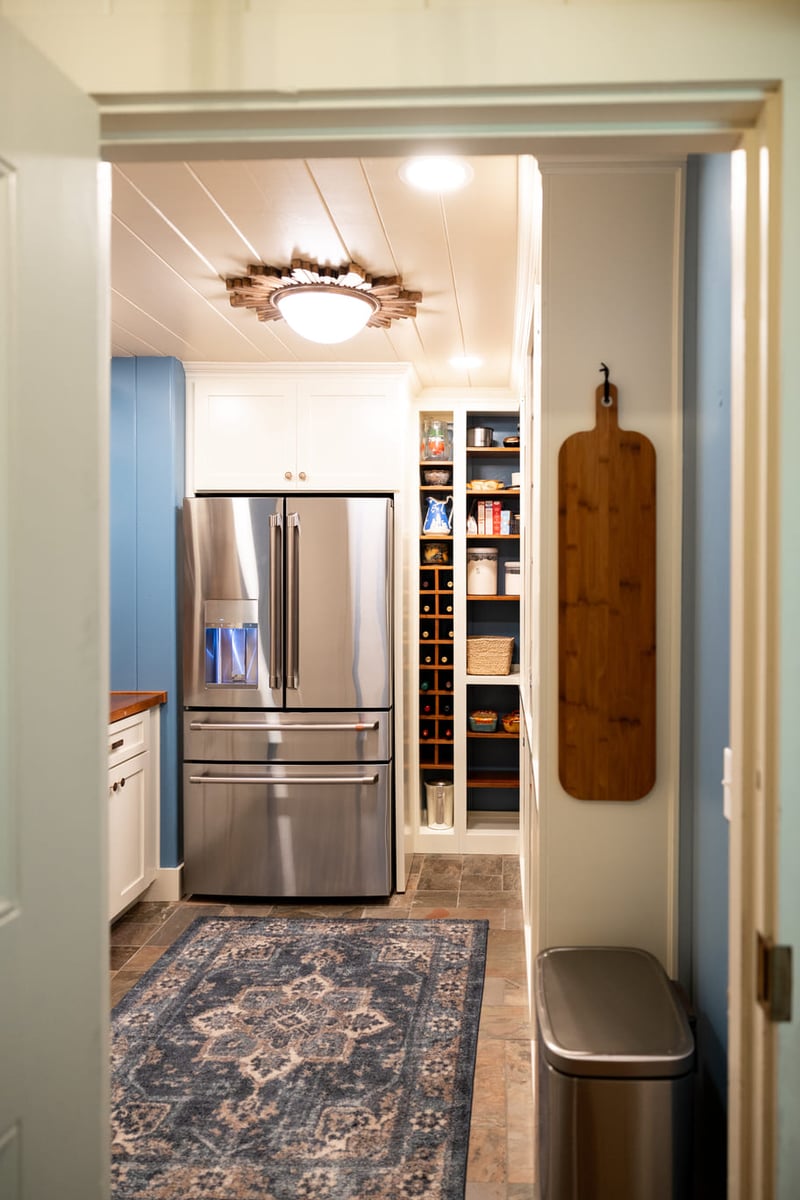 Refrigerator Kitchen with white cabinetry and wood countertops and shelves with blue and white walls and tiled floor with area rug