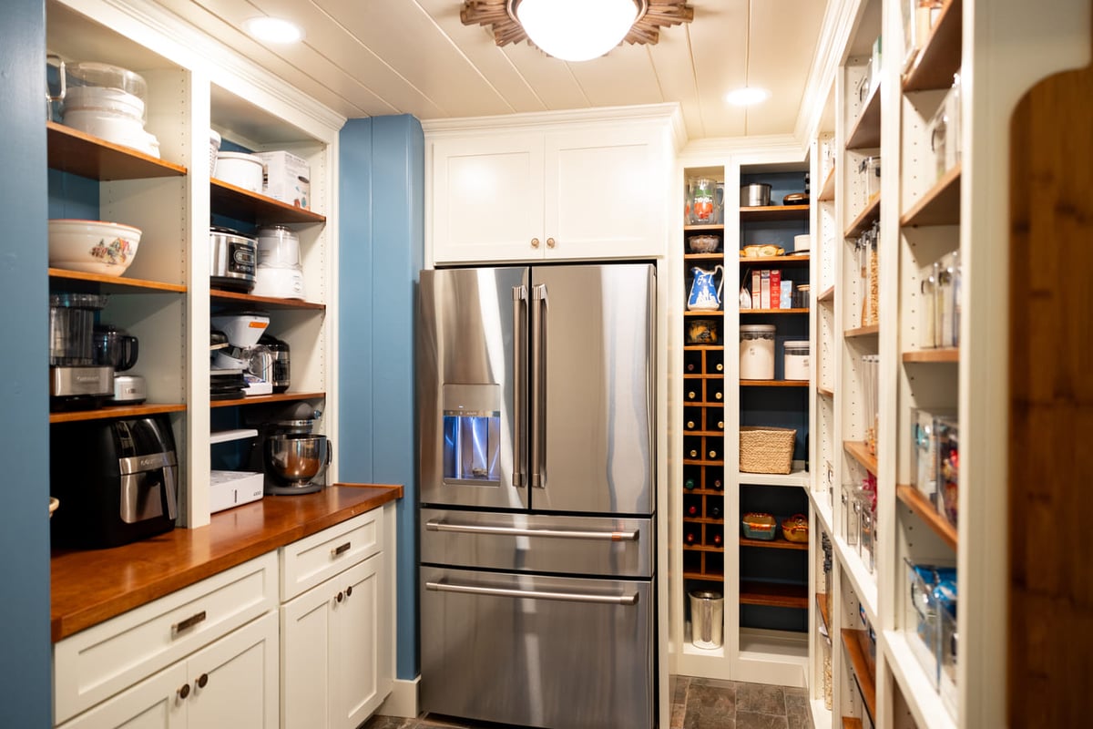 Refrigerator in well lit kitchen with white custom shelving and storage areas with light blue walls