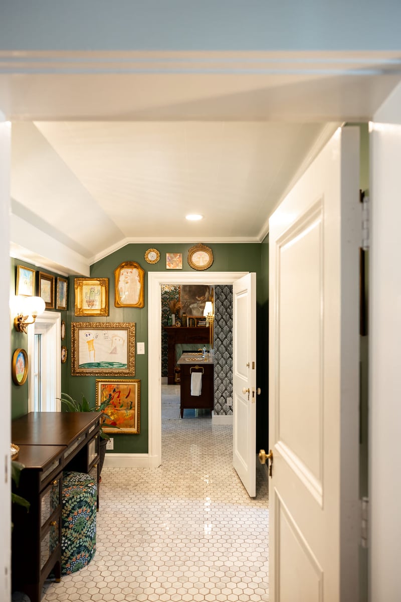 Vaniety area with white tiled floors and green walls and white molding leading to bathroom
