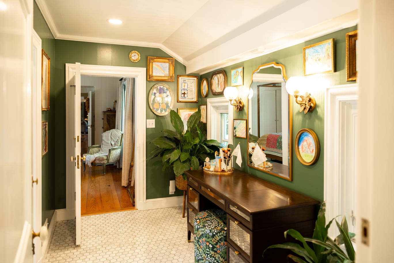 Vaniety with mirror and seating green walls with artwork hanging 