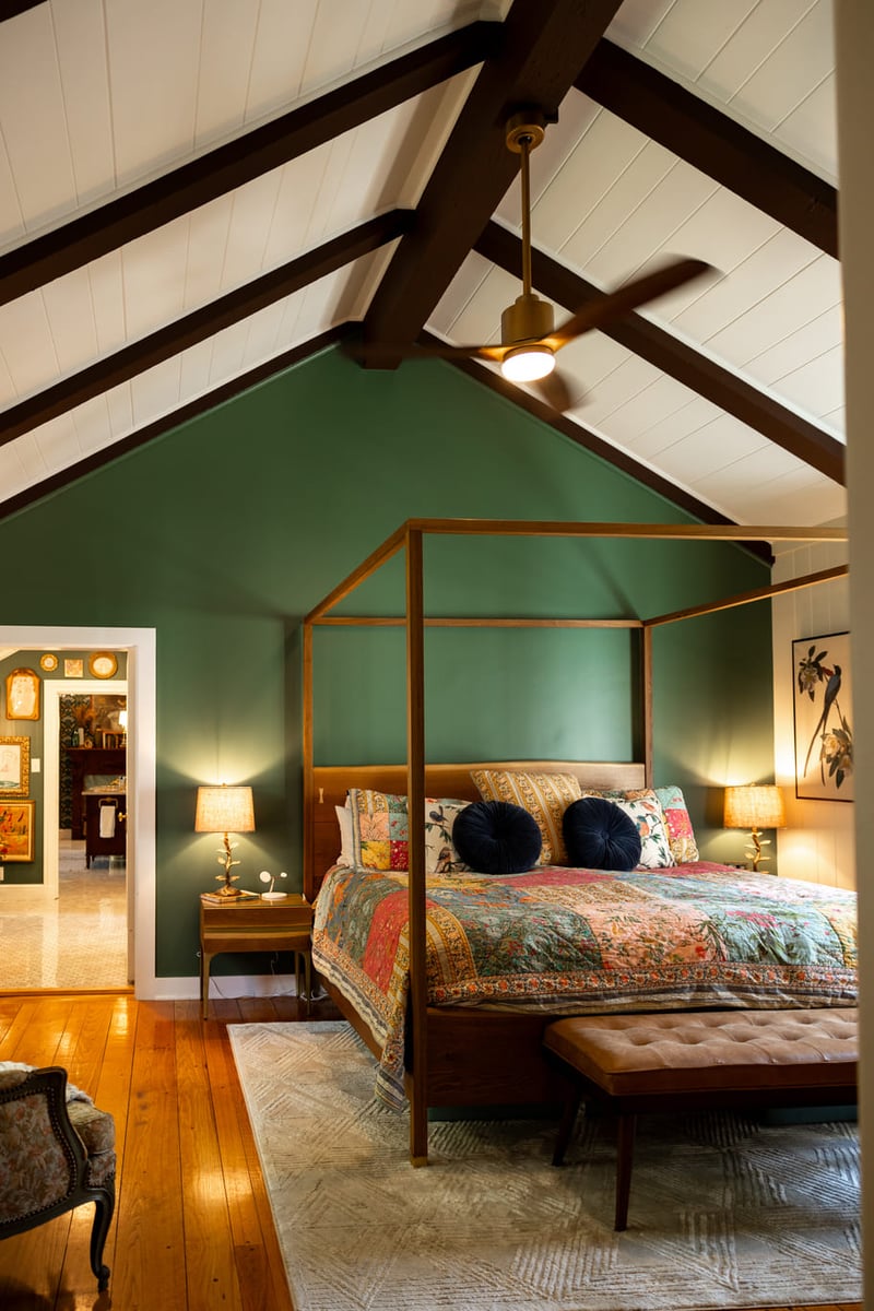 Vaulted ceiling bedroom with white and green walls and bed with canopy bedframe