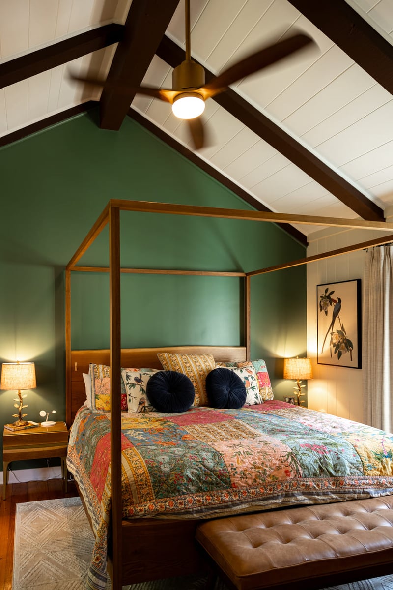 Wooden canopy bed frame in bedroom with vaulted ceilings and green walls 